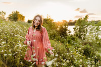Beautiful senior girl playing with flowers in a field near Green Bay
