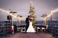 bride and groom kissing in front of christmas tree