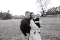 Mom and dad embrace young daughter during golden hour in Knoxville