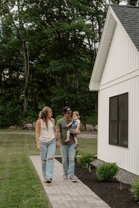 A loving family of three with mom, dad, and daughter sharing a joyful moment during a natural light family photo session by a Maine family photographer.