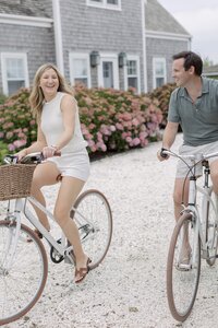 Couple smile as they ride bikes through Wauwinet, Nantucket.
