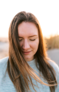 Romantisch en zacht portret van vrouw die naar beneden kijkt met wapperend haar