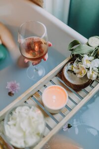 spa tub with flower petals and tray with candle and flowers