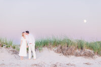 Couple holding hands and kissing on the beach near beach  grass