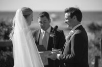 Bride and Groom looking at each other as they hold hands during wedding ceremony.