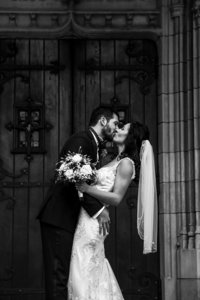 Bride and groom kissing outside the doors of the First Presbyterian Church of the Covenant in Erie, PA
