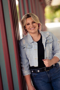 A young woman from Catholic Memorial High School leans against a building at Boerner Botanical Gardens wearing all denim for her senior portrait.