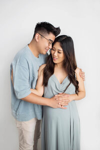 expecting couple smiling holding hands during studio maternity portrait session in Los Angeles