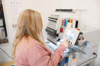Two women reviewing colorful thread samples in an embroidery workspace. Photograph by Yucaipa branding photographer Kaitlyn Dawn Photography.