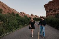 man and woman holding hands during engagement photos at red rocks park in colorado.