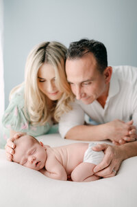 New parents looking down at their newborn baby sleeping Miami newborn photographer