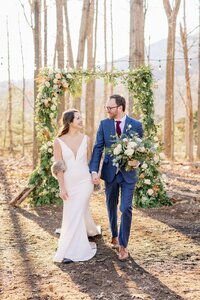 Couple walking through winter woods at styled shoot with floral design by Flowergirl Cville, Charlottesville area florist | Photo by Xiaoqi Li Photography