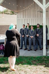 Mahlia taking photos of the groomsmen outside White Dove Barn
