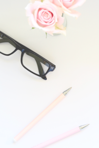 Flatlay of white desk with pens and glasses