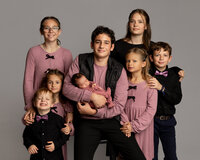 Studio family portrait of siblings gathered around and holding their newborn baby during a professional newborn photography session in Yucaipa by Kaitlyn Dawn Photography.