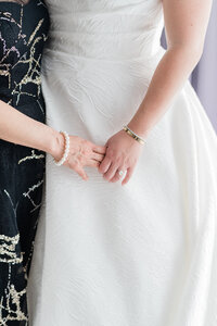 Bride and mother gently holding each other's hands