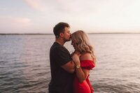 Groom kissing bride's forehead on the beach at sunset