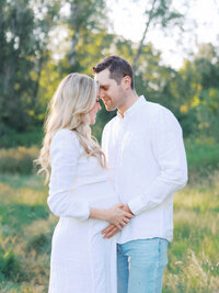 A couple embracing in Magnuson Park celebrating their pregnancy.