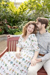 man and woman sitting on bench smiling while man is behind woman at belle isle detroit