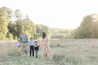 family hold hands while walking across field