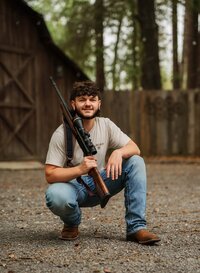 Senior portrait at Circle B Lake in Wilmer, Alabama — crouching in front of the old barn with an
unloaded hunting rifle resting on his shoulder.