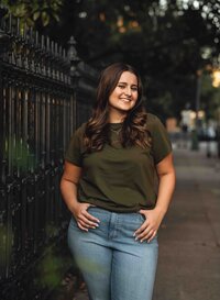 Senior girl posing by a black wrought-iron fence at Cathedral Square in downtown Mobile, Alabama.