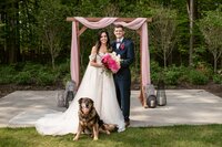 bride and groom standing with their dog in front