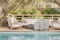 Three sizes of MUJI luggage staged poolside beneath olive trees