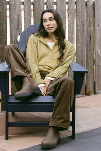 Chartreuse henley cardigan and brown corduroy trousers in an Adirondack chair