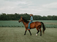 Senior portrait at Triple T Farms in Fruitdale, Alabama — riding her horse in a field.