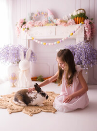 Little girl pets a live bunny during Easter Mini Session at Holy City Babies Portrait Studio in Charleston, SC.