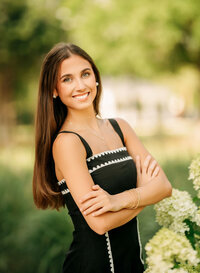 Senior portrait in downtown Foley, Alabama — waist-up in a black dress with white trim beside
limelight hydrangeas.