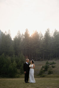 Newly married couple walking the grounds at tunnell mountain reservoir where they got married minutes before.