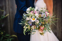 bride hugging groom while holding bridal bouquet