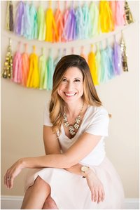 Female creative business owner smiles for photo in front of streamer covered wall