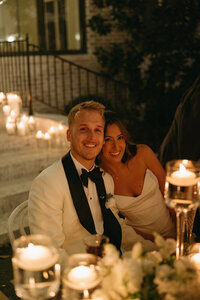 bride and groom smiling at camera from sweethearts table