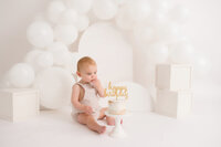 Baby eats smash cake during his first birthday Cake Smash Photoshoot at Holy City Babies Portrait Studio in Charleston, SC.