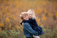 boy holding his little sister in a field photo taken by Detroit family photographer Kat Figlak