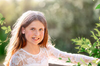 Close up portrait of child in white lace dress with soft golden backlight during outdoor family session in Eastern North Carolina