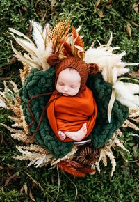 newborn baby wearing a knitted hat and sleeping in a wreath for his newborn session in Orange County
