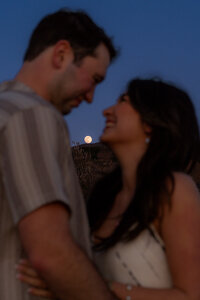 moonlit couple with moon behind on santa cruz beach