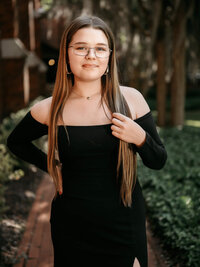 High school senior girl in black off shoulder dress posing in a garden setting in New Bern NC
