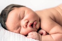 Sleeping newborn baby posed on gray backdrop in Eastern North Carolina