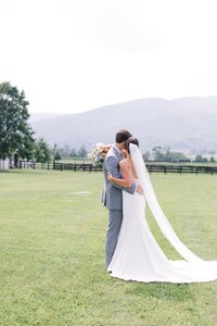 Bride and groom embracing on the vineyard lawn at King Family Vineyard, florals by Flowergirl Cville, Charlottesville wedding florist | Photo by Paige Ryan Photography