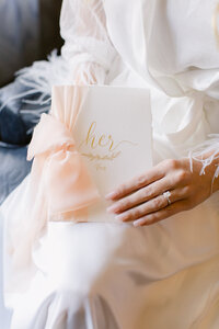 The bride holding a card and a closeup of her wedding ring.