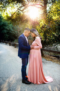 expecting couple in flowing dress during golden hour outdoor maternity portrait session