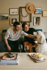 Couple with their dog in a guest room, wine and small plates on the table