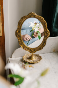Golden mirror with the reflection of hands holding a flower