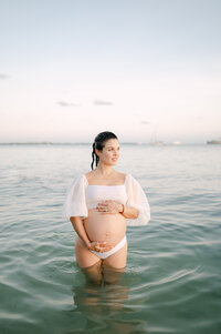 Expecting mother gazing at ocean during Miami maternity session