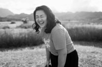 A black and white photo of someone leaning over and laughing